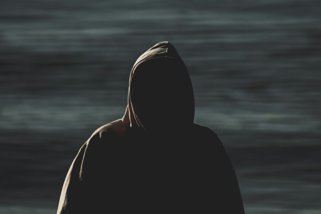 A dark mysterious silhouette of a hooded figure Cybersecurity: What Is the Dark Web? (2025 Guide)